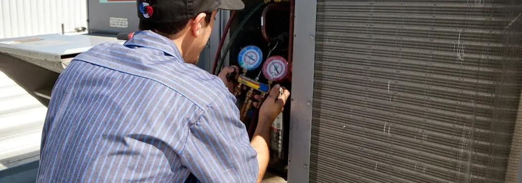 HVAC technician servicing a condenser unit in Belleville